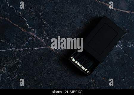 black matches with a white head in a black box on a marble background Stock Photo