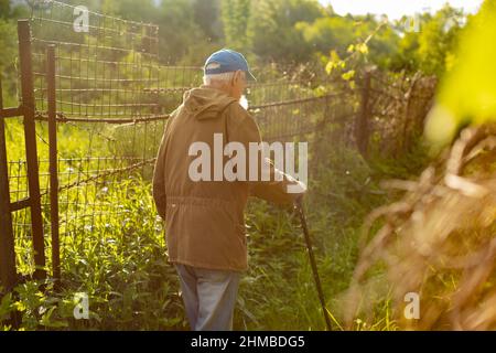 An old man with a walking stick. A Russian old man in the countryside. A man who is over 90 years old. Pensioner in Russia. Stock Photo