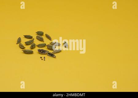 Dry green cardamom seeds, Elettaria cardamomum. Cardamom pods on yellow background. Organic herbs and spices Stock Photo