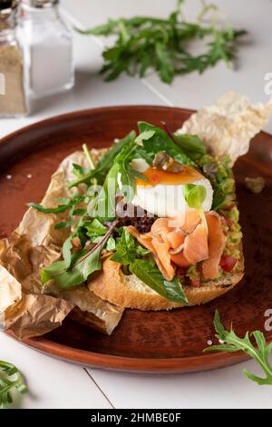 Bruschetta with avocado, salted salmon, microgreens and poached egg, Closeup Stock Photo