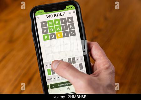Brandon, MS - February 8, 2022: Hands playing Wordle game on phone. Stock Photo