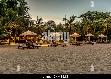 Bali beach with sunbeds at night and people relaxing in the restaurant, Bali, April 26, 2018 Stock Photo