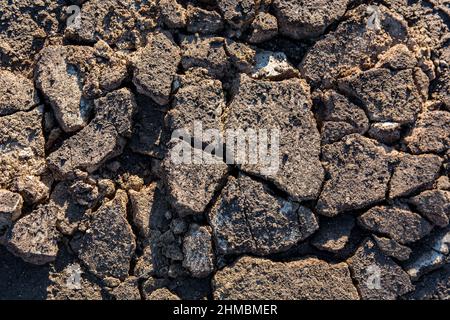 Cracks on the surface of the earth are altered by the shrinkage of mud due to drought conditions of the terrain. Close up, top view Stock Photo