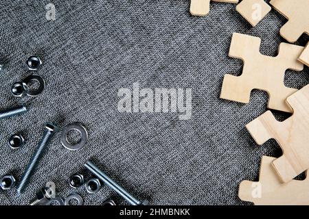 puzzle elements and and steel nuts, bolts on a textile background top view Stock Photo