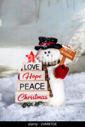A chubby snowman holds two signs, to celebrate Christmas in the snow Stock Photo