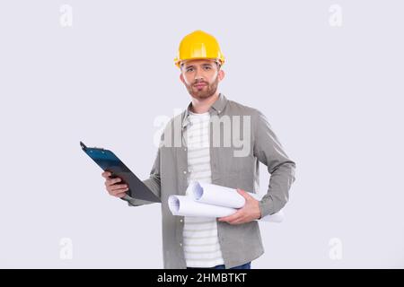 Construction Worker Holding House Plan and Clipboard in Hands. Architect Holding Blueprints. Yellow Hard Helmet. Worker Serious Face Stock Photo