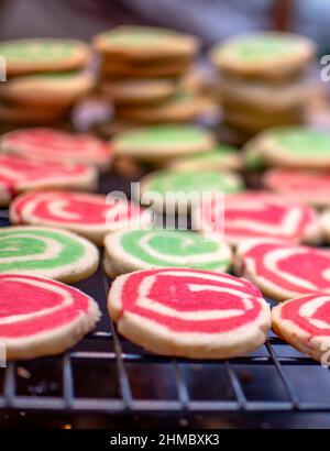 red and green spiral cookies cool on a rack during Christmas baking Stock Photo