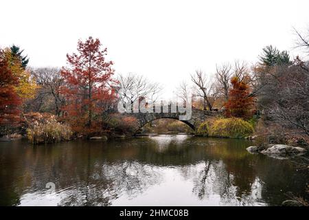 Fall foliage and the iconic Gapstow Bridge overlooking the Pond and Hallett Nature Sanctuary in the southeast corner of Central Park, New York. Stock Photo