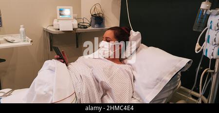 pregnant young woman dilating in delivery room, using smartphone Stock Photo