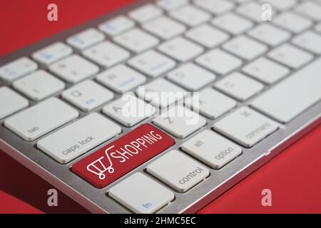 Closeup shot of shopping text on a computer keyboard isolated on red background Stock Photo