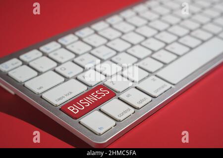 Closeup shot of business text on a computer keyboard isolated on red background Stock Photo