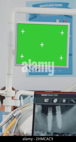 Woman working as dentist with green screen and x ray scan for teethcare in dental cabinet. Oral care specialist analyzing chroma key with isolated mockup template and teeth radiography Stock Photo