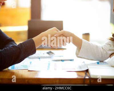 Two successful and professional businesswomen are shaking hands over office desk. Business partnership, Agreement, Close the deal. cropped shot Stock Photo