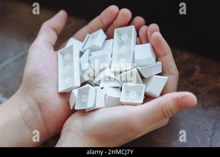 top view closeup of Caucasian child hands holding many pbt keycaps of a white mechanical keyboard in natural lighting Stock Photo