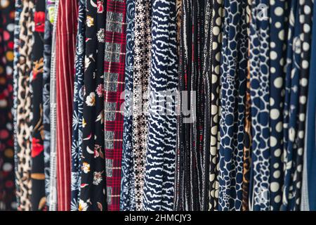Large rows of pieces of fabric made of cotton, polyester, and other materials in different colors and prints of clothing, soft focus Stock Photo