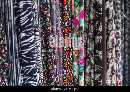 Large rows of pieces of fabric made of cotton, polyester, and other materials in different colors and prints of clothing, soft focus Stock Photo