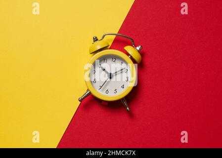 Yellow alarm clock on a yellow, blue, red and green background. Copy space. Time concept. Stock Photo