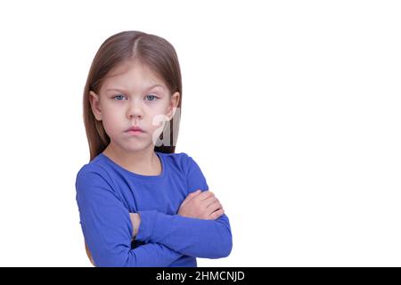 Serious child kid holding crossed hands isolated on white background, looking at camera waist up caucasian little girl of 5 years in blue Stock Photo