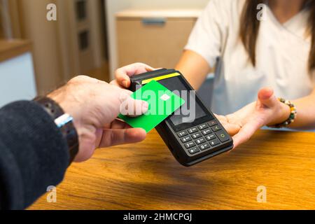 Man paying with credit card via payment terminal in clinic Stock Photo