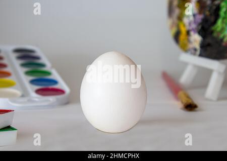 White Easter egg on a watercolor background. Simple holiday composition. Symbolism of the Easter egg festival concept. Art work, handmade, creativity Stock Photo