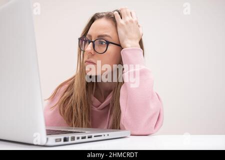 young woman student professional in glasses looking at laptop at home office feel stressed frustrated online work Stock Photo