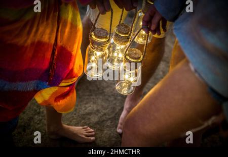 Hipster friends having fun together at beach camping party - Friendship travel concept with young people holding neon led lanterns at summer sea camp Stock Photo