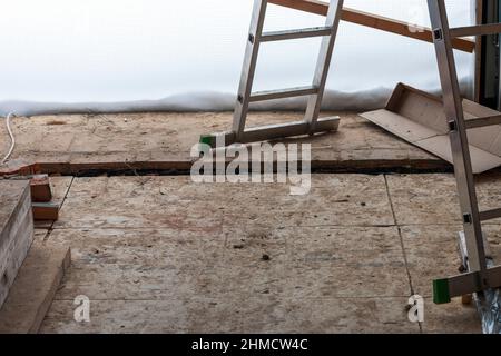 expandable aluminium ladder on the dirty floor of unfinished building Stock Photo