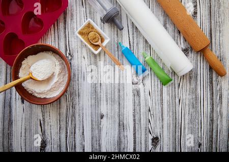 Preparing for baking: heart-shaped silicone mold, rolling pin, confectionery syringe, glaze, flour, sugar. Copy space. Stock Photo