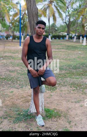 Young man in the park leaning against the tree Stock Photo
