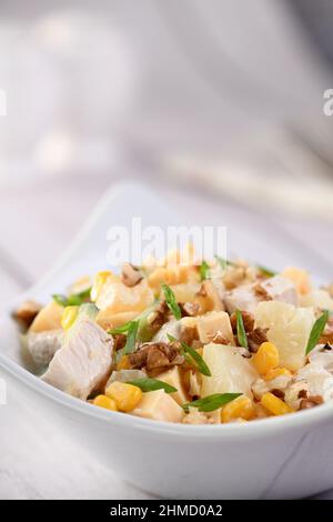 Chicken salad with pineapple, corn and cucumber dressed with Greek yogurt, crushed nuts and cheese. Stock Photo