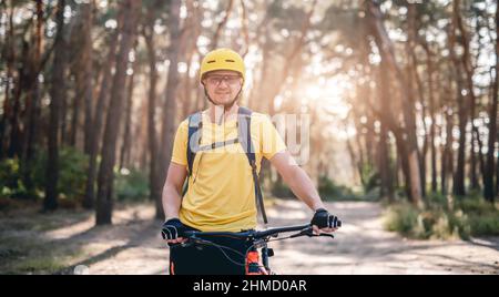 Cyclist standing with bike in forest Stock Photo