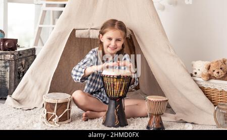 Little girl playing on djembe drums Stock Photo