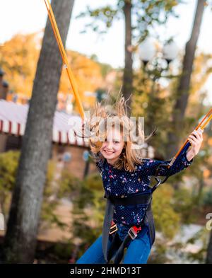 Smiling little girl jumping on trampoline rope Stock Photo