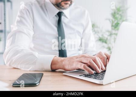 Male entrepreneur using laptop in office, closeup of hands typing the portable computer keyboard with selective focus Stock Photo