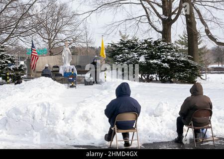 BAYSIDERS. Devout Christians attend a winter afternoon mass in a park in Queens New York at the site of the 1964 Worlds Fair Vatican Pavilion. Stock Photo