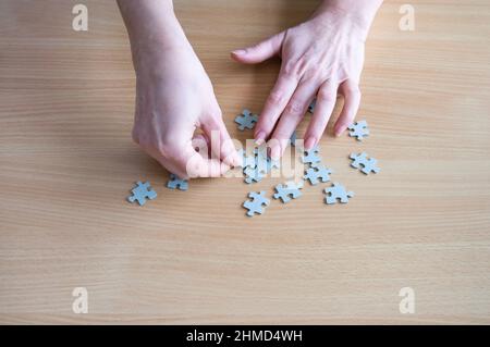 Hands arranging puzzle pieces on table Stock Photo