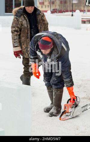 Worker with a chainsaw in hand at the assembly site Stock Photo