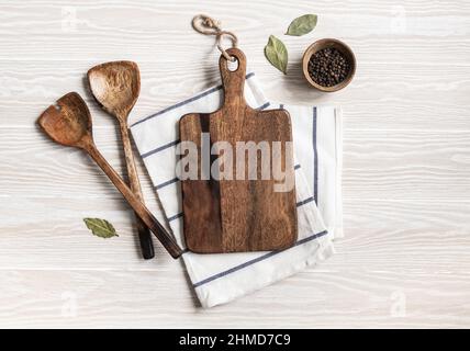 Minimal wood white kitchen background with brown cutting board, various spices, appliances and cotton napkin. Kitchen utensils on texture white table. Stock Photo