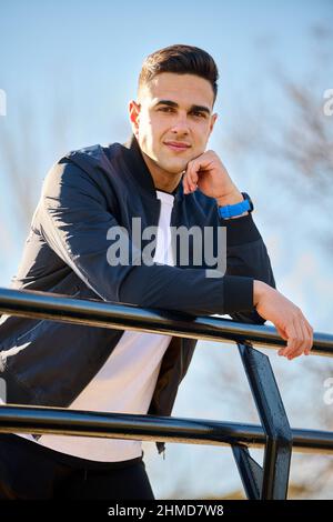 Young handsome man in casual clothes sitting in the city park after playing sports Stock Photo