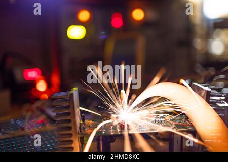 A dark green electronic printed circuit chip for TFT, with bright multi-colored wires lies on the wooden table of a talented engineer and sparkles wit Stock Photo