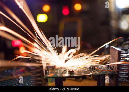 A dark green electronic printed circuit chip for TFT, with bright multi-colored wires lies on the wooden table of a talented engineer and sparkles wit Stock Photo