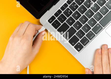 Woman plugging charger in a laptop. Type C charging port. Low battery concept Stock Photo