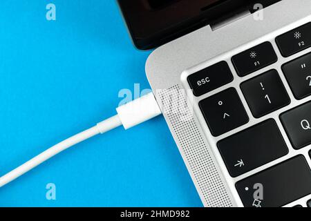Charging laptop with modern USB Type C port. Laptop low battery concept, technology background, office table top view Stock Photo