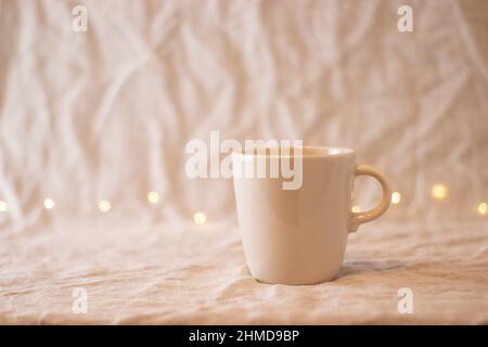 beige empty coffee mug, on fabric, isolated background Stock Photo