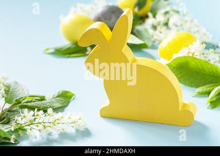 Happy Easter concept with rabbit, natural colorful easter eggs and spring flowers on a blue background. Easter background. Stock Photo