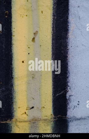 Old black yellow paint with cracks on brick wall as background, texture, selective focus Stock Photo