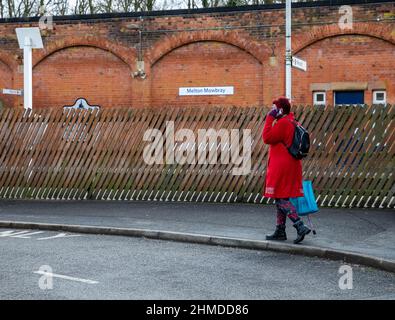 Melton Mowbray,Leicestershire,UK,9th February 2022,A lady talks on her mobile phone outside Melton Mowbray Railway Station on a grey and cloudy day.Credit: Keith Larby/Alamy Live News Stock Photo