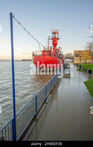 High water at spring tide overflowing the sea wall on the banks of the Thames at Gravesend Kent with LV 21 moored by riverside Stock Photo