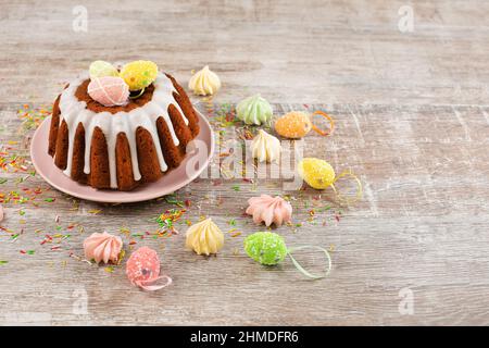 Glazed easter cake decorated with mini eggs candy on wooden table. Happy Easter Holidays. Copy Space Stock Photo