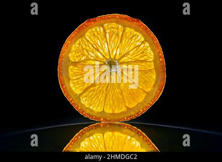 Slice of a orange isolated in dark black bacnground with reflection Stock Photo